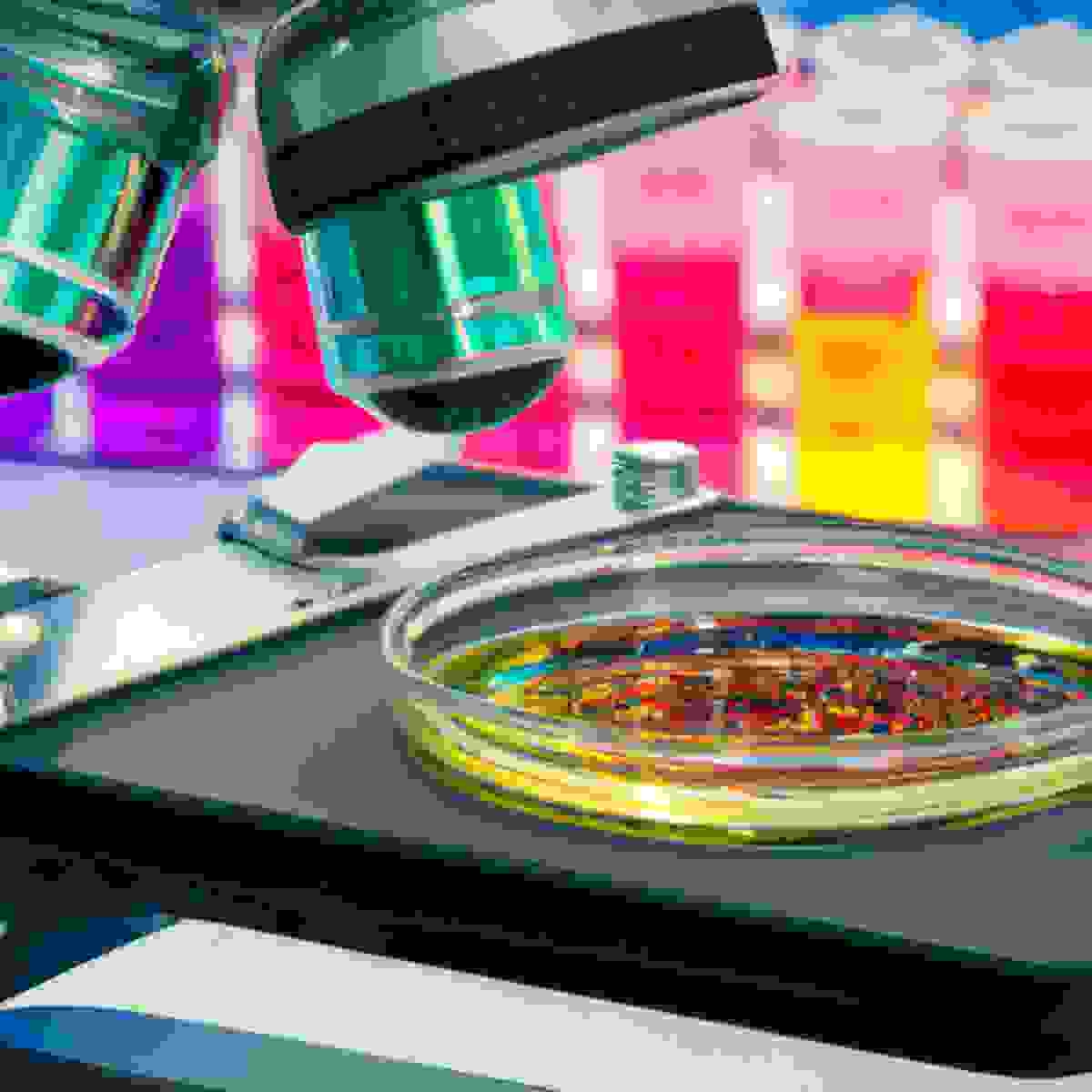 Close-up of state-of-the-art microscope focused on vibrant, multi-colored solution in petri dish, surrounded by scientific instruments, conveying hope and progress in Harlequin Ichthyosis treatment research.